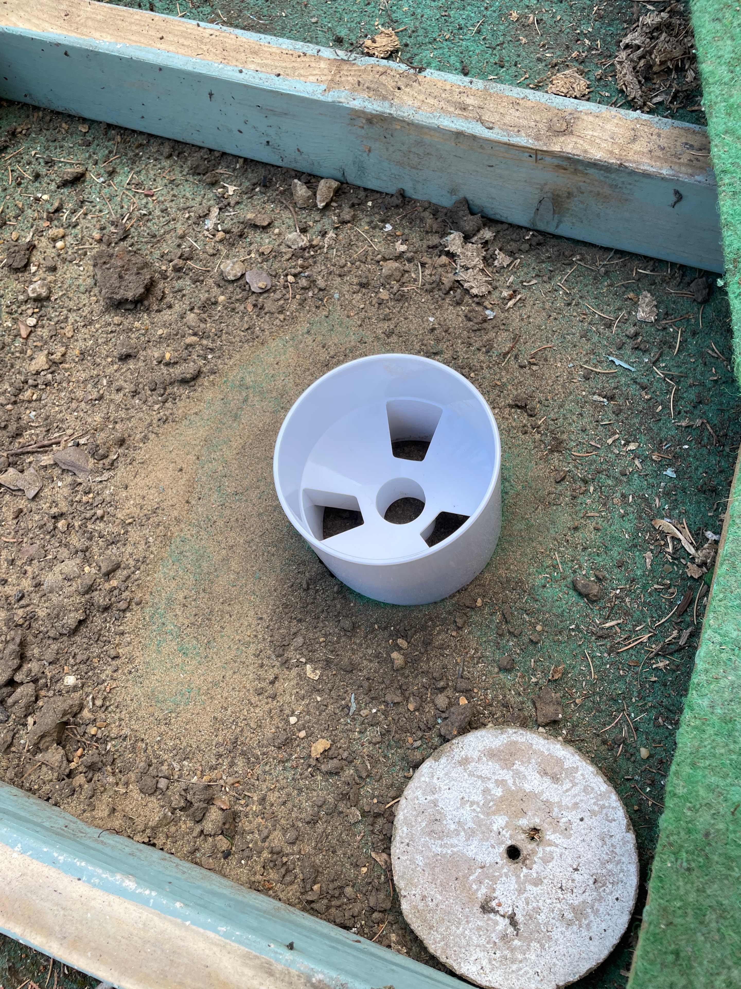 Hole cup being set into the base frame during putting green installation